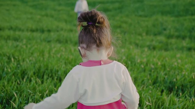 A little boy and a little girl running towards each other on the field and embrace