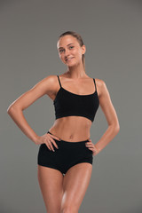 Fototapeta premium Muscular young woman athlete on gray