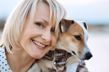 Beautiful blonde girl with a smile and a dog. Happy face
