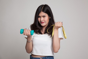 Exhausted  Asian woman with dumbbells and measuring tape.