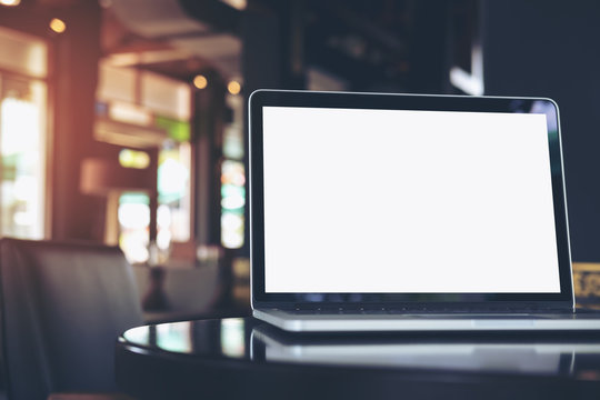 Mockup image of laptop with blank white screen on wooden table in coffee shop