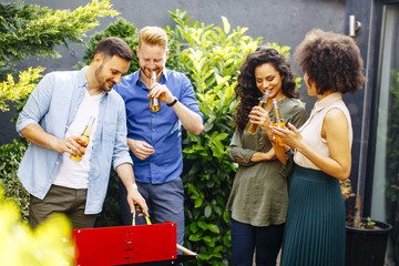 Happy friends grilling food and enjoying barbecue party outdoors