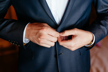 man fastens his jacket. Groom getting ready. Businessman putting on his jacket