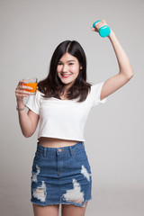 Young Asian woman with dumbbell drink orange juice.