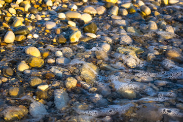 sea pebble beach with multicoloured stones, waves with foam