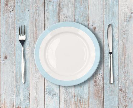white empty dinner plate with blue border on wooden table