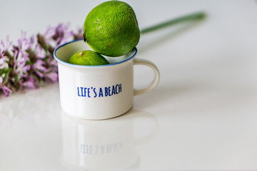 Close-up of a glass with a handle full of whole lime, prepared for juice. Focusing on the glass. Shallow depth of focus. Concept Summer.