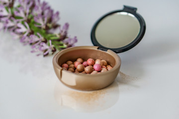 Close-up of makeup pearls, pink and purple on white background. Shallow depth of focus. Concept fashion beauty.