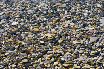 sea pebble beach with multicoloured stones, waves with foam