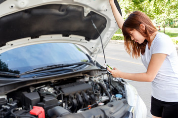 Stressed woman taking photo of engine with mobile phone - car breakdown.