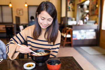 Woman enjoy udon in Japanese restaurant