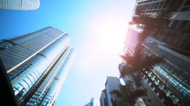 Smooth low angle tracking shot of office buildings with sun flare reflection. ood for video establishing shot, video opening or closing.