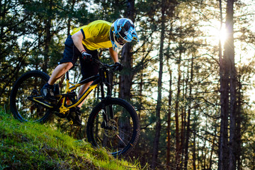 Fototapeta na wymiar Professional Cyclist in Yellow T-shirt and Helmet Riding the Bike Down Hill in Forest. Extreme Sport Concept.