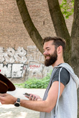 Cheerful and handsome hipster with beard smiling holding his mobile phone