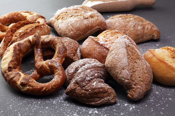 Different kinds of bread and bread rolls on board from above. Kitchen or bakery poster design.