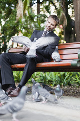 Obraz premium Businessman feeding pigeons in park