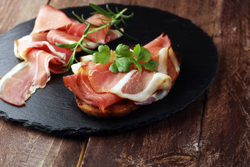 Bread with slices jamon serrano for lunch table. Sharing antipasti on party or summer picnic time...