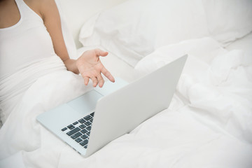 Close up woman hand with laptop on her bed.