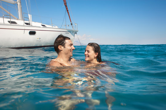 Young Couple Swimming In Sea By Yacht