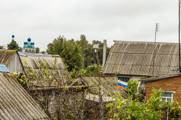Fototapeta na wymiar Roofs of the old beggar patriotic home ownership of the old Russian village. Russian flag in a ramshackle slum.