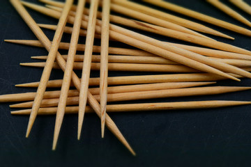 Some wooden toothpicks on black background. Macro.