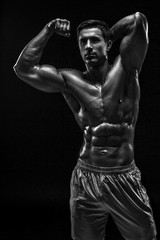 Muscular and fit young bodybuilder fitness male model posing ove