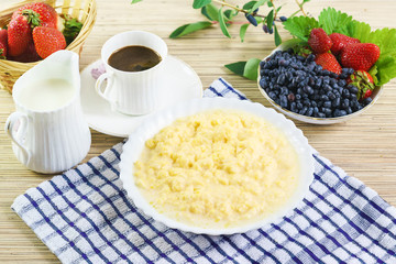 Corn porridge with milk, a Cup of coffee and the berries of honeysuckle and strawberries.