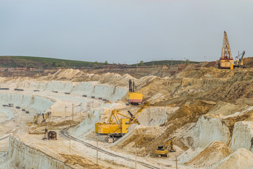 Work of heavy grab and bucket excavators in the chalk quarry. Heavy mining industry.