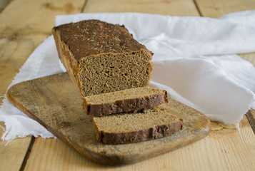 Rye bread on the board and wooden table with white napkin.