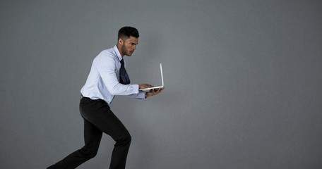 Composite image of businessman using laptop while running 