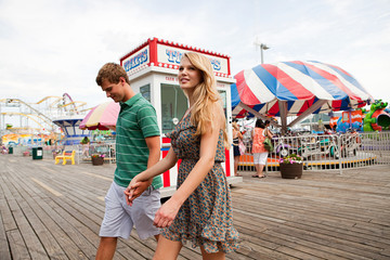 Teenage couple at boardwalk fun fair - obrazy, fototapety, plakaty