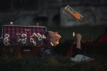 Woman sorceress lies and reads a book. Levitation.