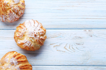 Homemade profiteroles with cream on white wooden table