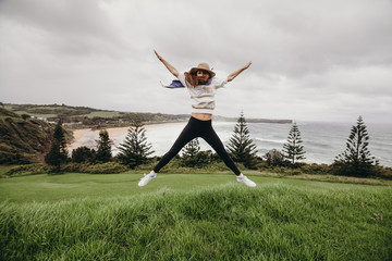 Fototapeta na wymiar Woman jumping in front of a beautiful beach in Australia.