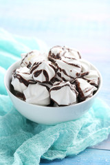 Meringue cookies with chocolate in bowl on wooden table