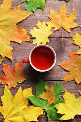Autumn leafs with cup of tea on brown wooden table