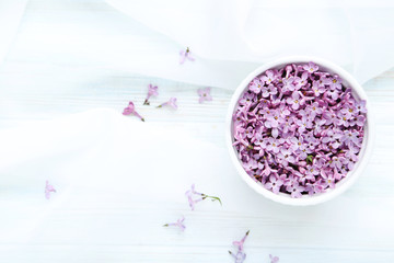 Fototapeta na wymiar Lilac flowers in bowl on white cloth