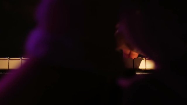A piano player holds a glass of wine while playing - Close up