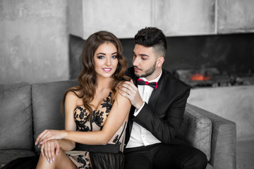 Woman in elegant dress sitting with handsome man in black suit.