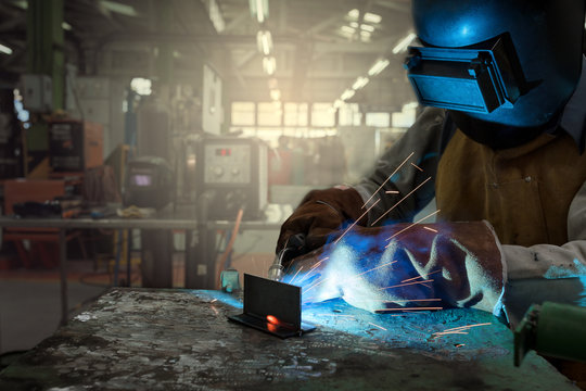 Masked worker Welding steel with gas in the factory during the operation by wearing a safety uniform for gas welding.