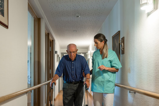 Nurse helping senior man with walking frame to get to his room in retirement home