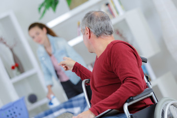 Man in wheelchair giving instructions to young lady