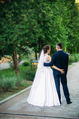 Fototapeta premium Beautiful couple walking in the park in their wedding day. Sunny weather.