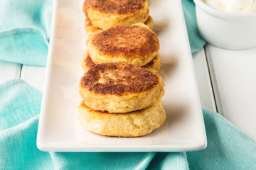 Cottage cheese pancakes on a wooden white background, horizontal, selective focus
