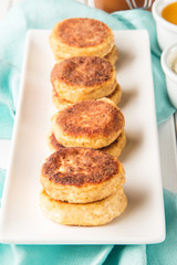 Cottage cheese pancakes on a wooden white background, vertical, selective focus
