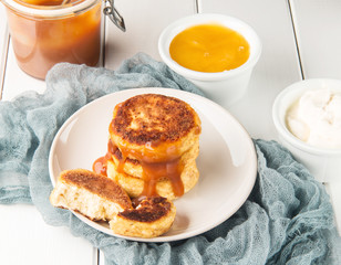Cottage cheese pancakes on a wooden white background, horizontal, selective focus
