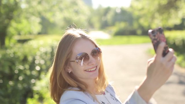 Pretty girl in sunglasses taking selfie with a smart phone