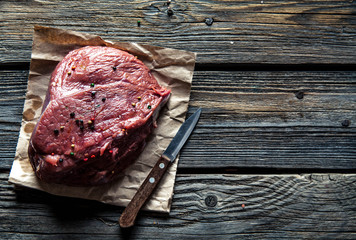 Meat with spices and vegetables on wooden background. Knife. food