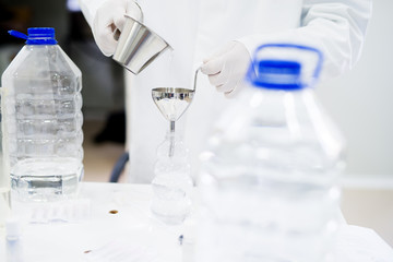 Lab technician doing water analysis, dressed in protective sterile equipment. Drinking water production.