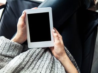 A girl holding a tablet in hands, reader with a nice manicure. Leather trousers, ugg boots. Fashion, style, learning, modern, recreation